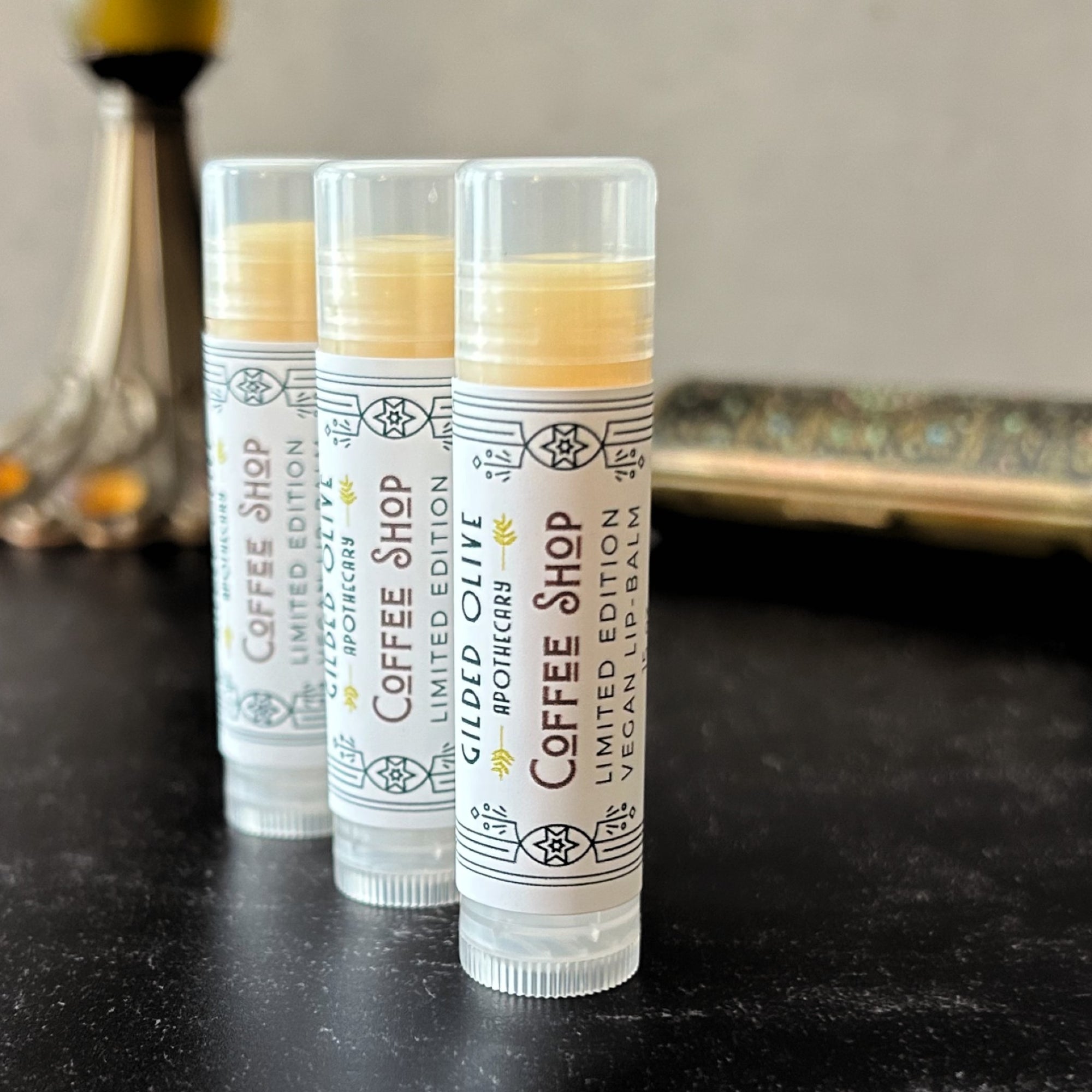 3 Coffee Shop Vegan Lip Balms on a dark surface