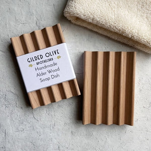 Wooden soap dish with soft beige towel on a gray surface