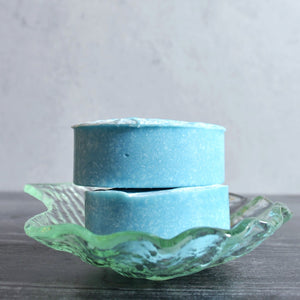 Blue soap on a sea shell dish against a gray background
