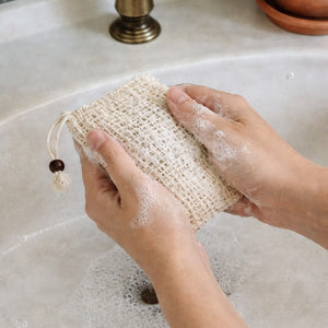 Person washing hands with a soap saver bag at a sink.