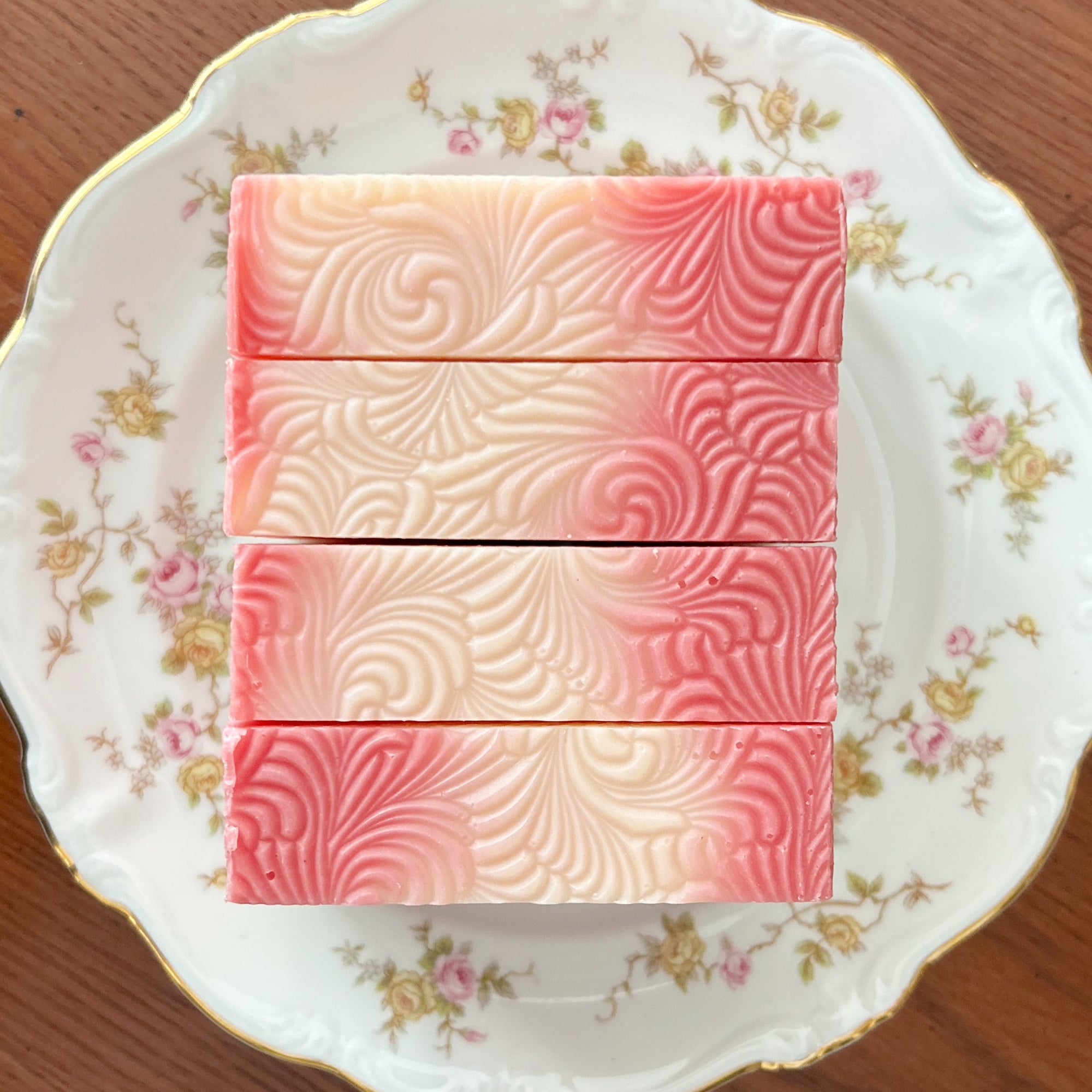 Grace Note pink and white patterned soap tops on a decorative plate with floral designs.