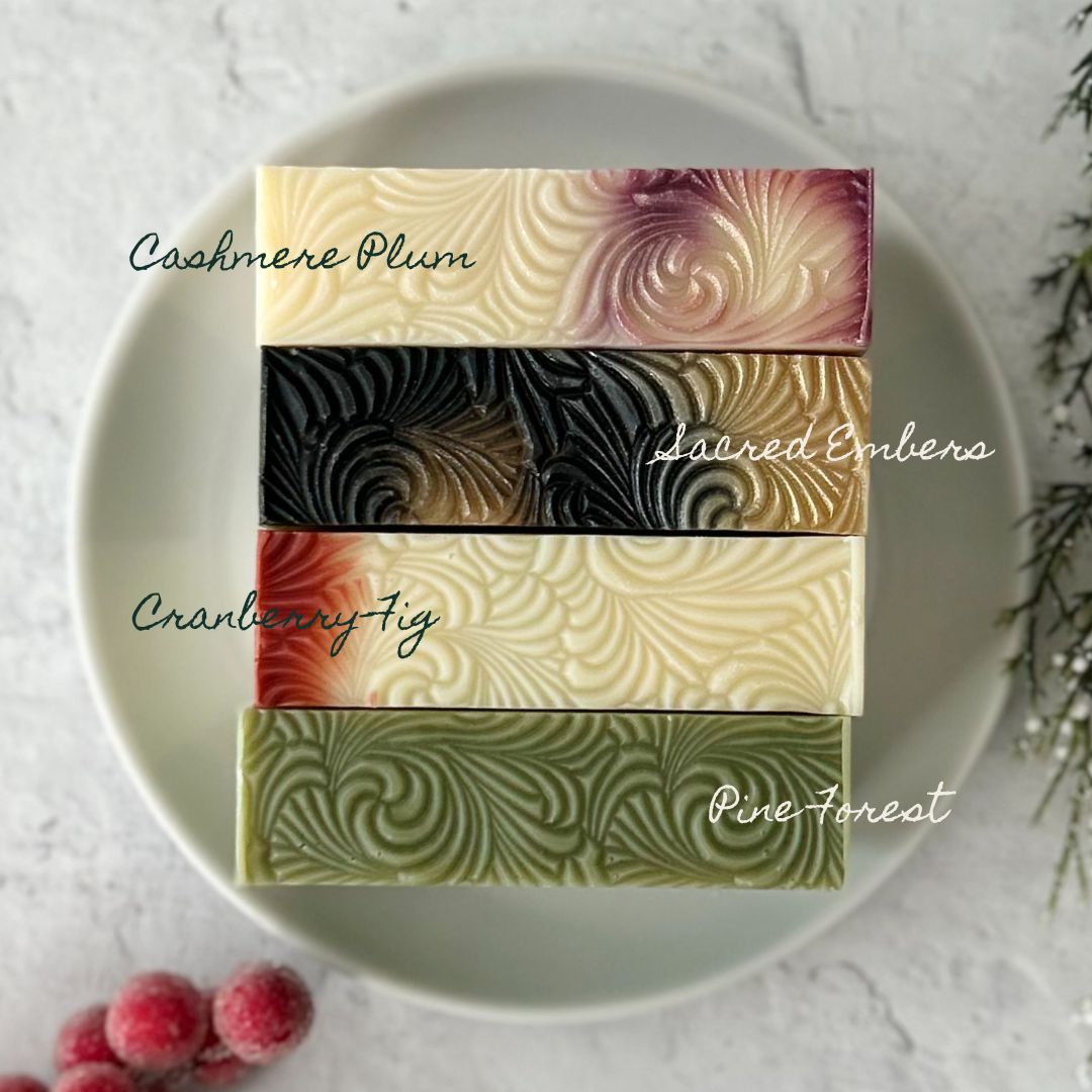 Holiday themed soaps with textured patterns on a white plate, with a light background.