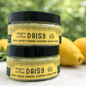 Two jars of Daisy Fresh Lemon Verbena Whipped Sugar Scrub with lemons in the background.