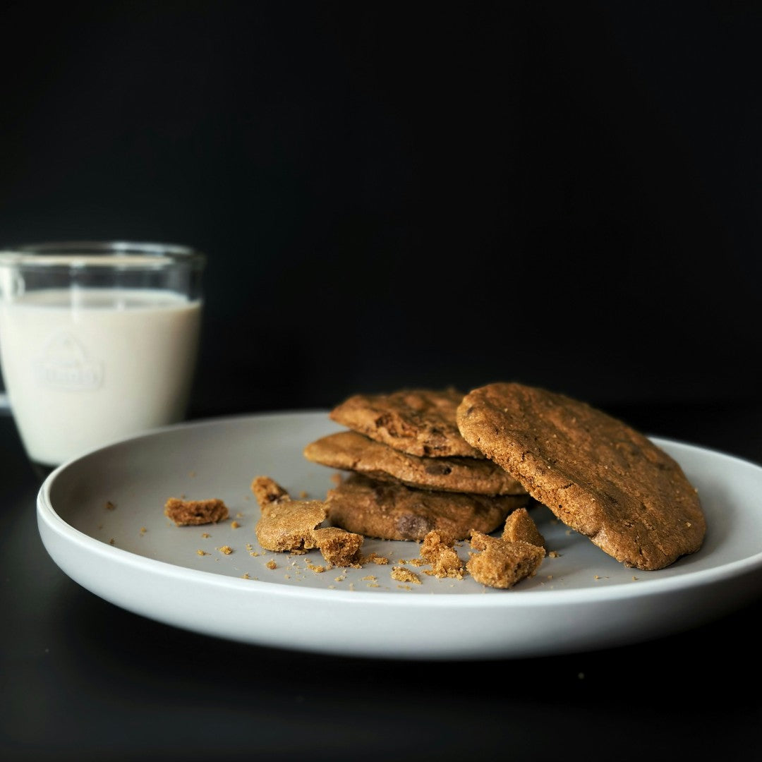 Oatmeal cookies on a plate with a glass of milk against a black background