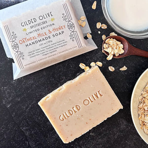 Oatmeal Milk & Honey Handmade Soap styled with oats and milk on a dark textured background.