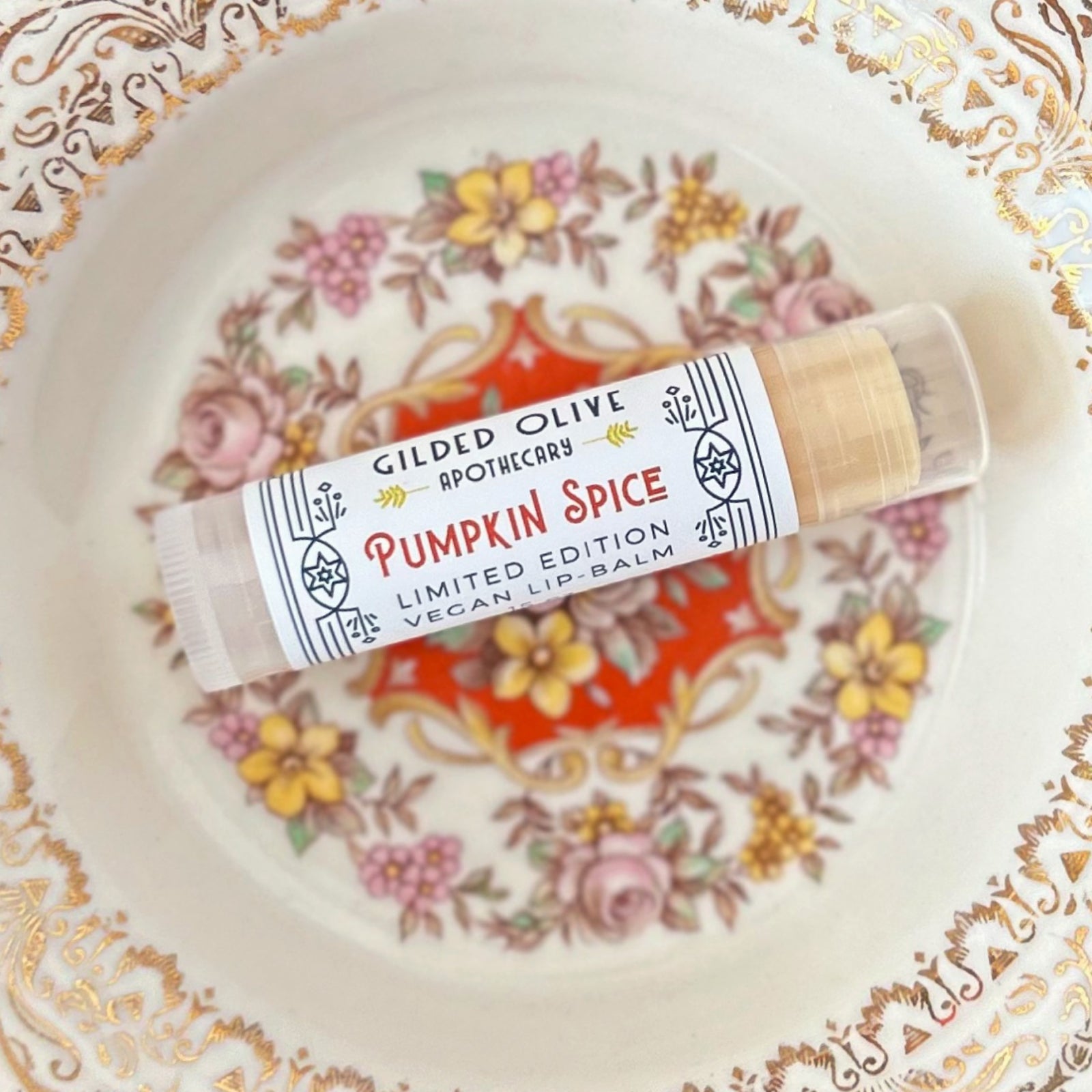 A single tube of Pumpkin Spice Lip Balm, on an antique dish