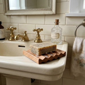 Vintage style bathroom sink with soap on a wooden soap dish with a decorative towel.