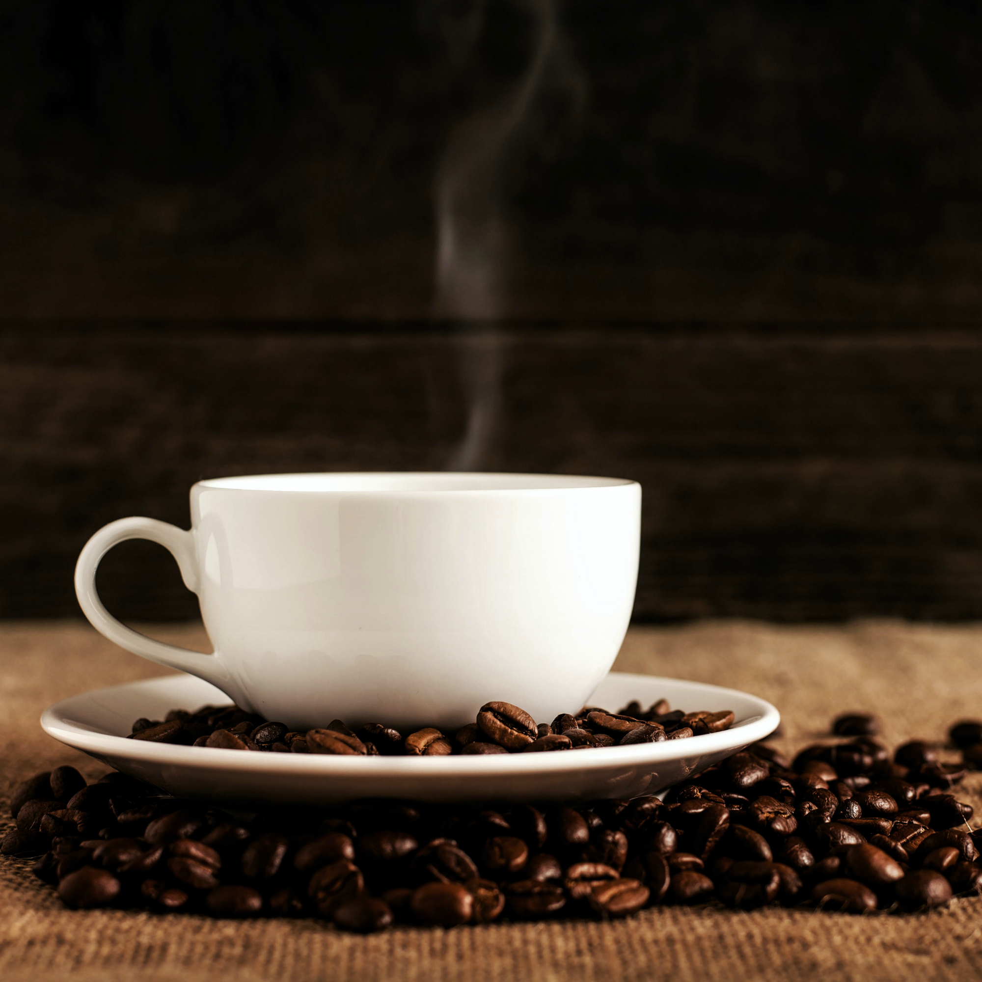 A cup of hot coffee with coffee beans