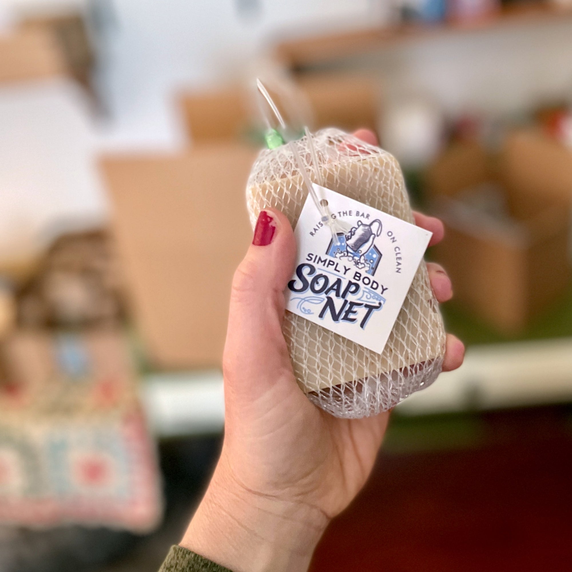 Hand holding a Simply Body Soap Net with handmade soap in it
